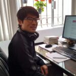 メキシコの観光ガイド岩﨑功がパソコンの前でポーズをとっている