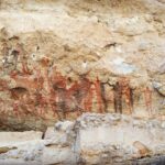 赤と黒で岩絵が描かれている
