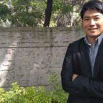 メキシコの観光ガイド岩﨑功が石碑の前で腕組みをしている