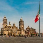 メキシコシティのソカロで風にたなびく国旗と日を浴びる大聖堂カテドラル