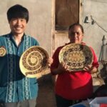 メキシコガイドの岩﨑功と現地の女性が民芸品を持っている